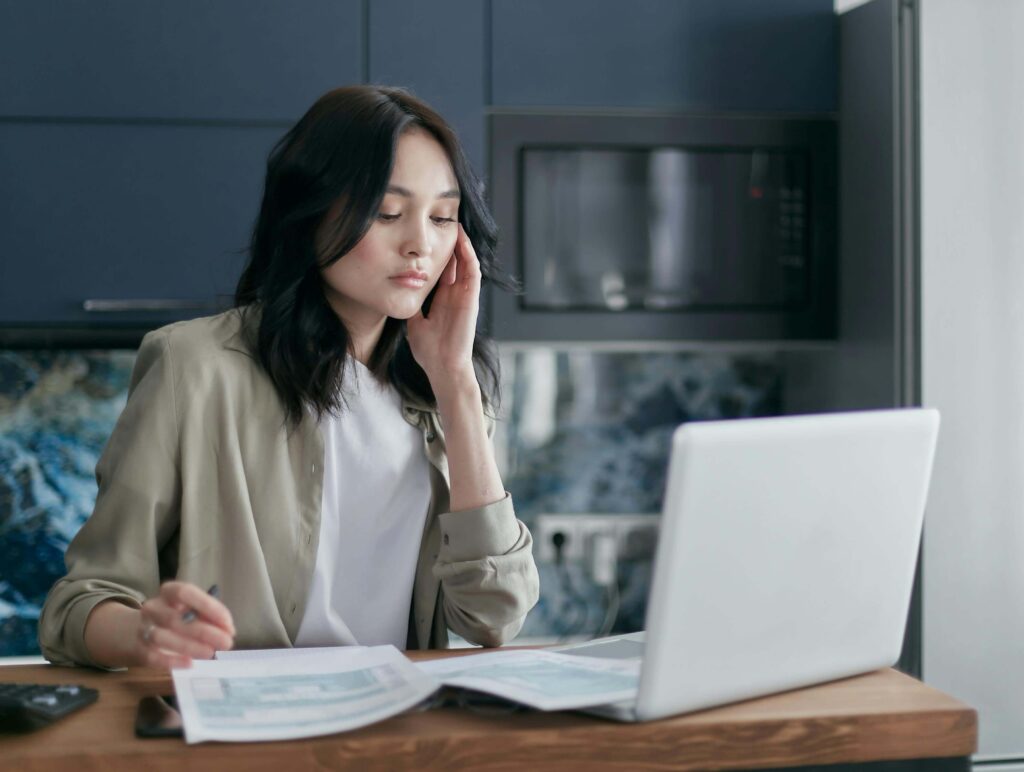 A woman reviewing her credit score report on a laptop, planning to improve her credit in 2026
