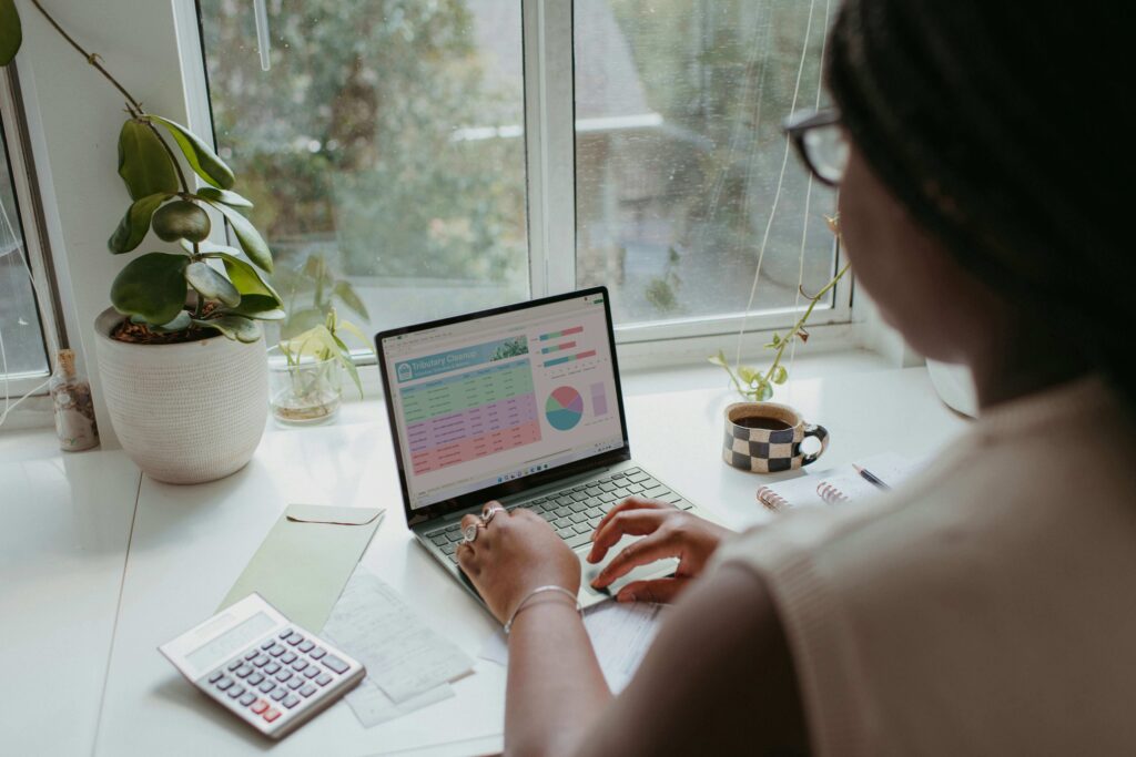 A woman reviewing her credit score on a laptop while taking notes on credit-building strategies