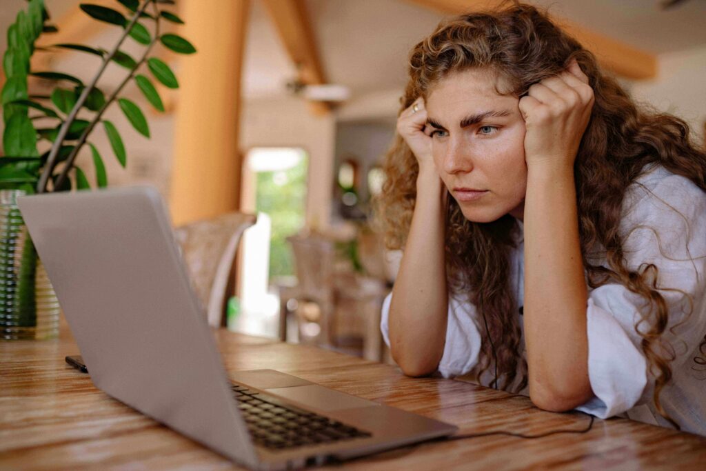 Woman reviewing her credit report on a laptop, looking for late payment errors to dispute