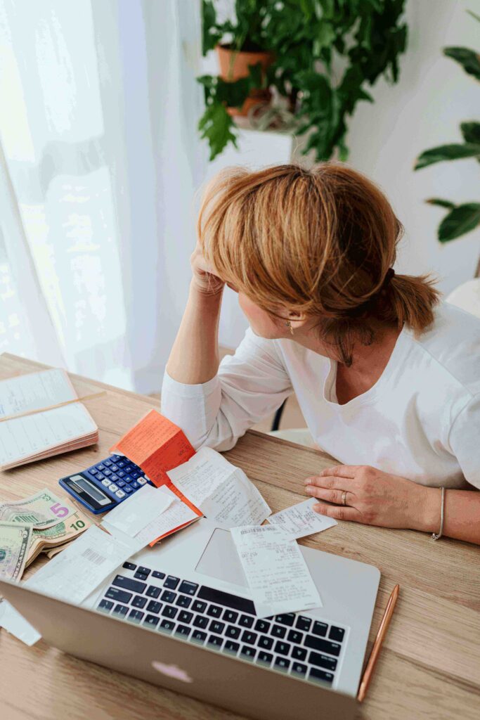  A woman sitting at a kitchen table reviewing her monthly budget and credit card statement on a laptop