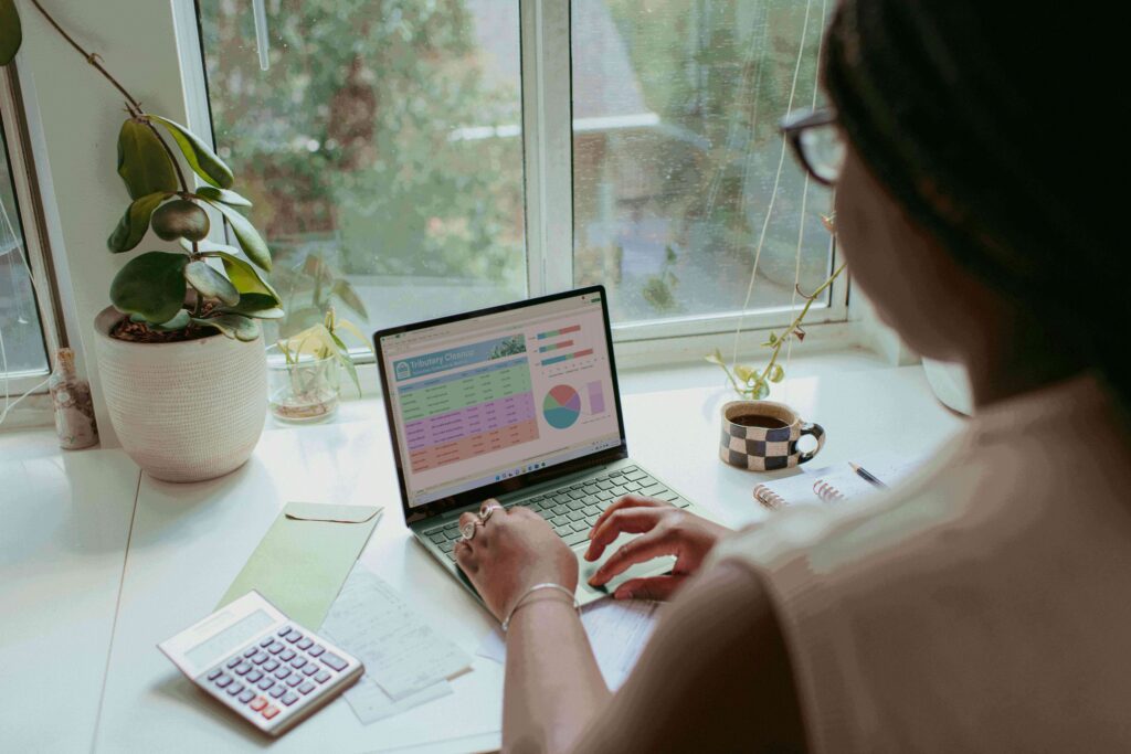 Young woman reviewing her credit score on a laptop and taking notes, planning her credit-building strategy