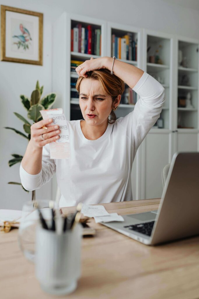 Woman looking stressed at laptop reviewing credit card bill after missing a payment