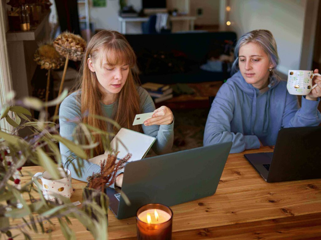 A college student sitting at a desk reviewing credit card options on a laptop, learning how to apply for their first credit card in the U.S.