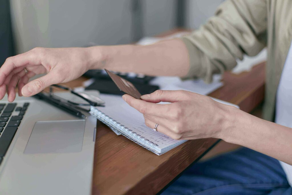 A person reviewing credit card options on a laptop at a kitchen table, representing getting a credit card on a low income in the USA