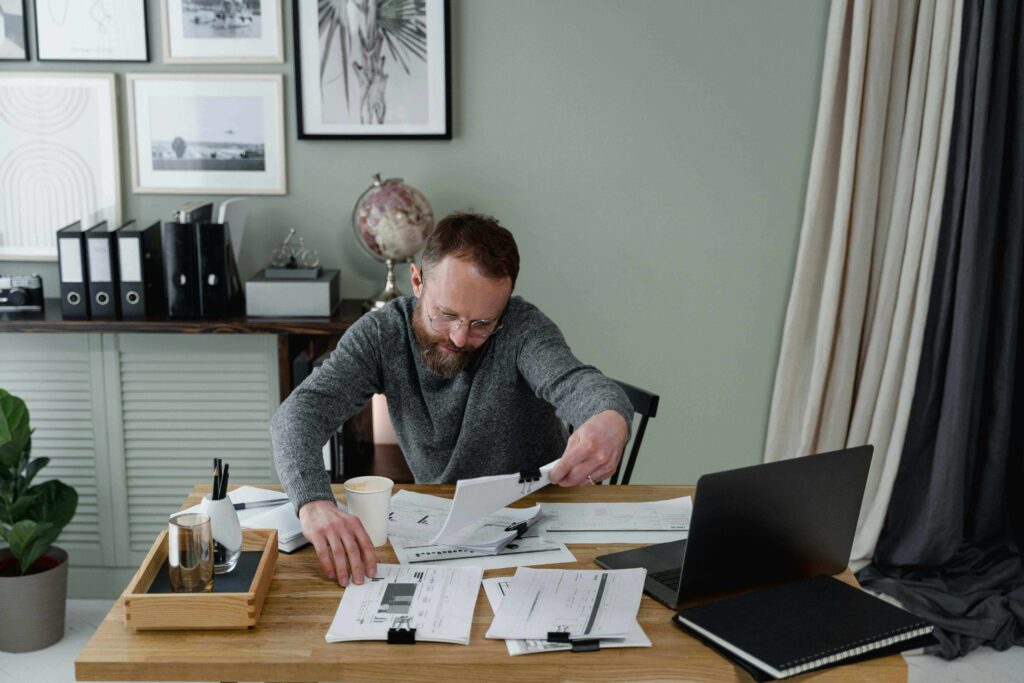 man reviewing his credit report on a laptop, looking concerned about a charge-off entry